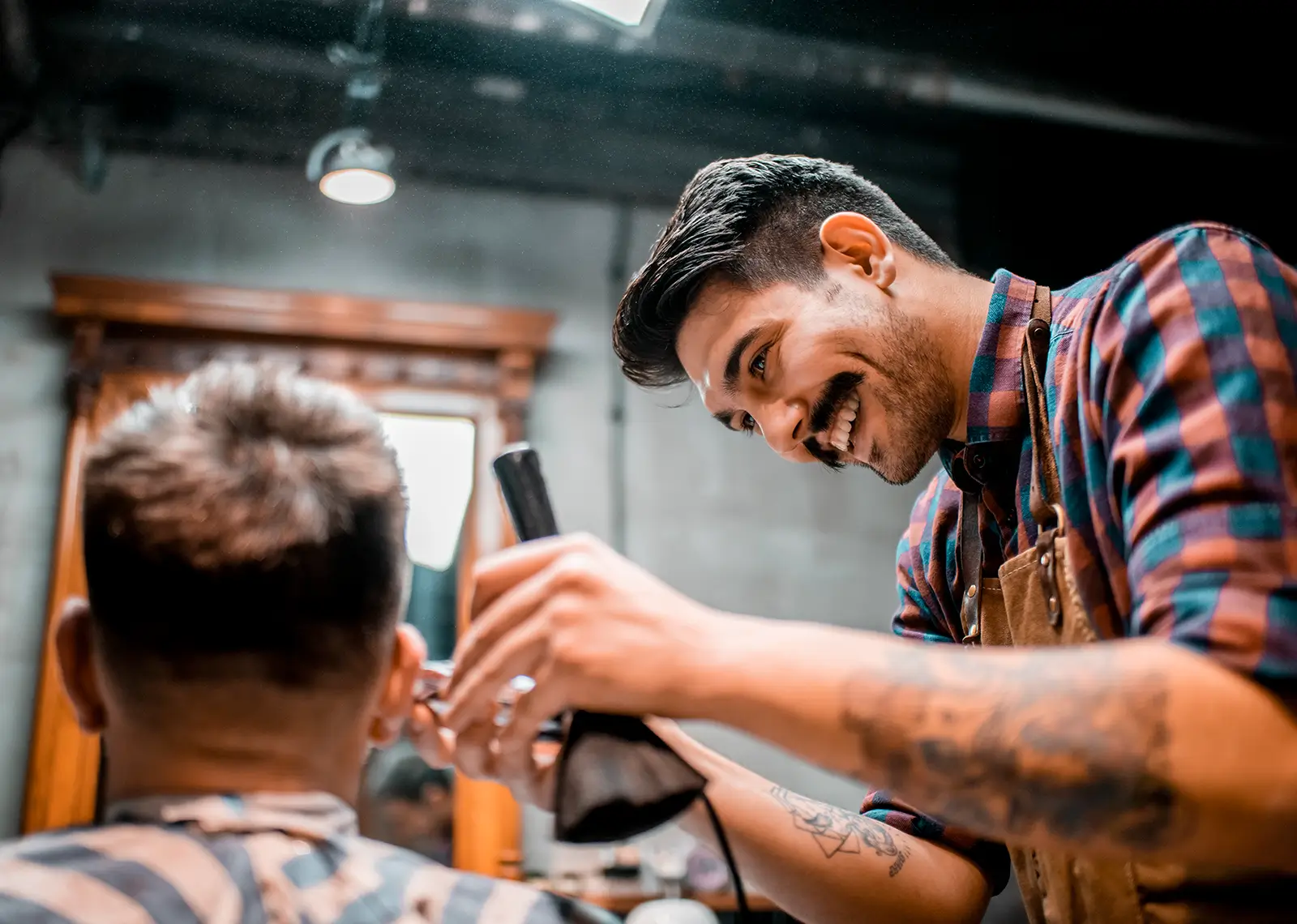Barber cutting a client's hair with clippers in a barbershop setting